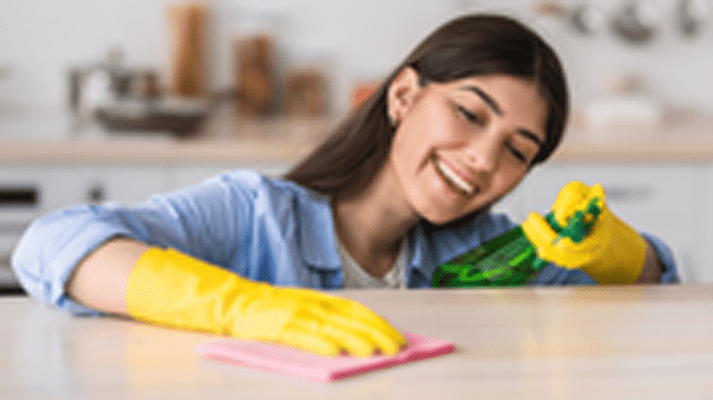 Woman shown energetically cleaning a stone countertop